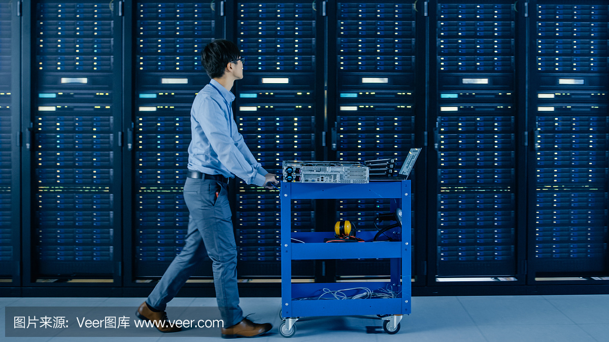 在现代数据中心:IT工程师推着购物车在服务器机架和机柜旁边安装新的硬件,用于计划的系统更新和设备更换。